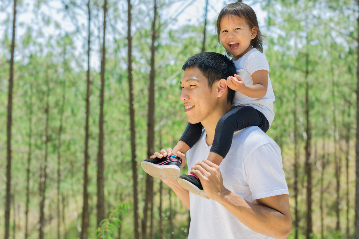 Father and daughter playing outside in a green forest