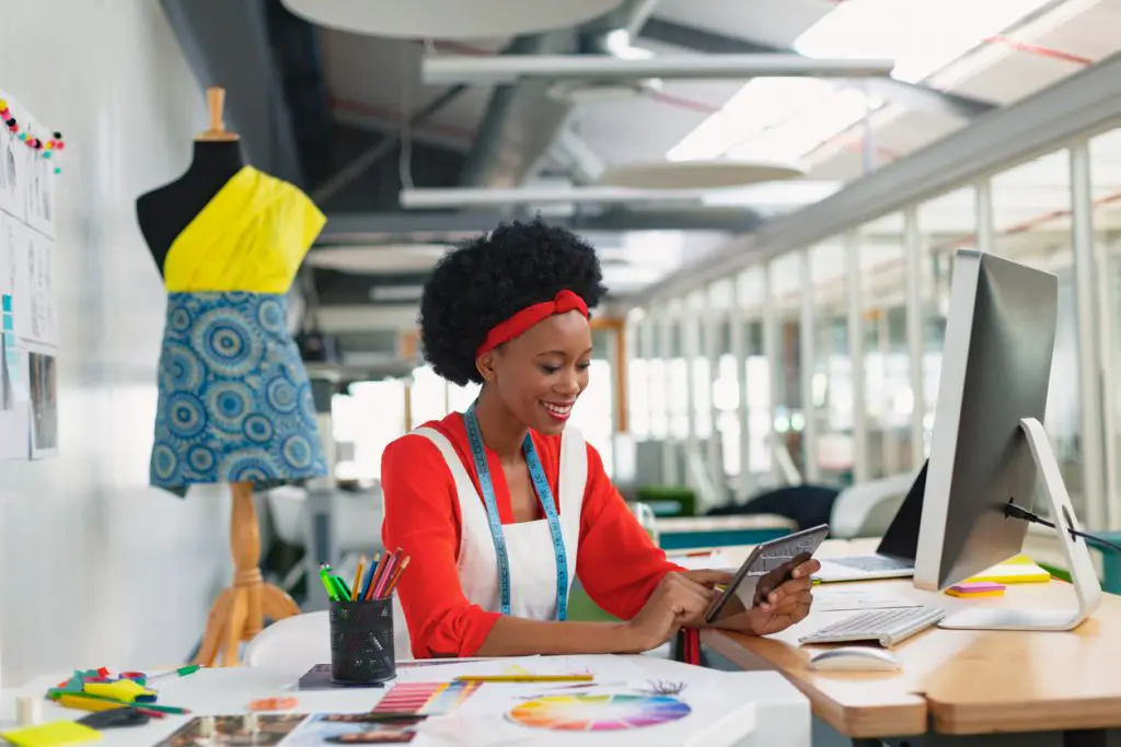 Female fashion designer using a digital tablet at desk in her office.