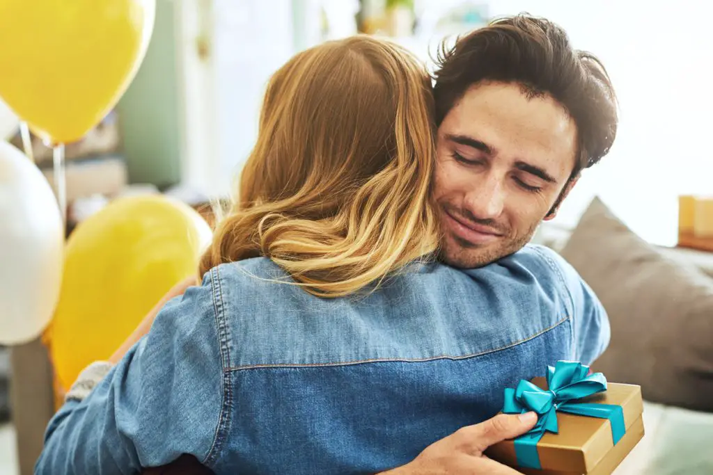 Couple hugging with a present.