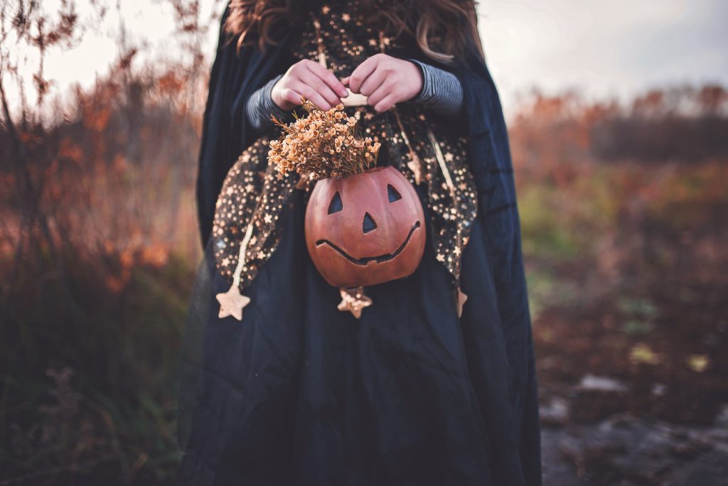 Girl with pumpkin. Photo by Paige Cody on Unsplash.